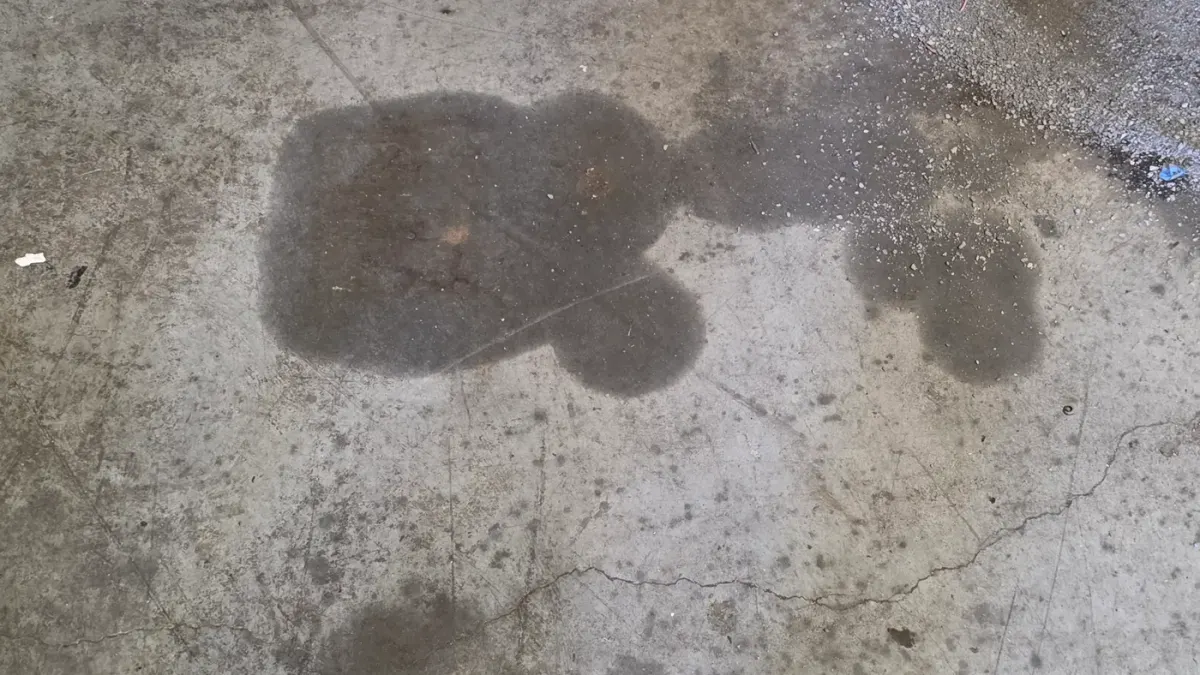 Before: oil soaked into bare concrete beside a car lift, with cracks and swept grit